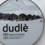 Installazione circolare che raffigura la Via dei Fienili di Dosoledo e la scitta Dudlè, ovvero il nome del paese in dialetto ladino e le scritte Regola di Dosoledo e Gruppo di Ricerche Culturali di Comelico Superiore