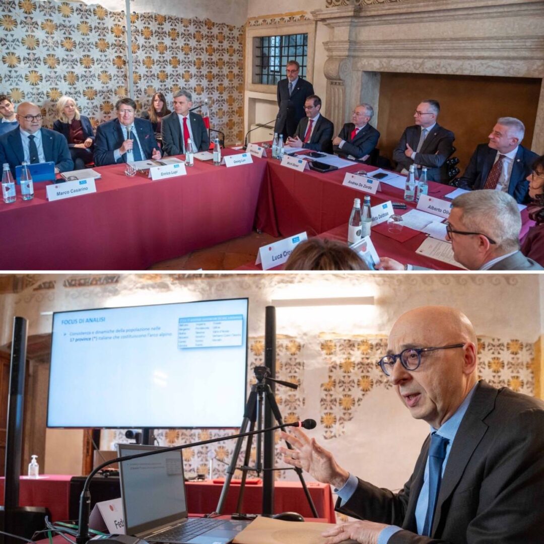 Assemblea Alps con rappresentanti seduti a un tavolo a ferro di cavallo e sotto la foto del Dott. Callegari che parla al microfono