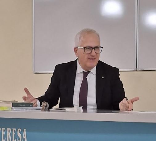 Foto di Marco Zabotti direttore Istituto Beato Toniolo. Seduto al tavolo dei relatori mentre parla. Veste giacca nera cravatta