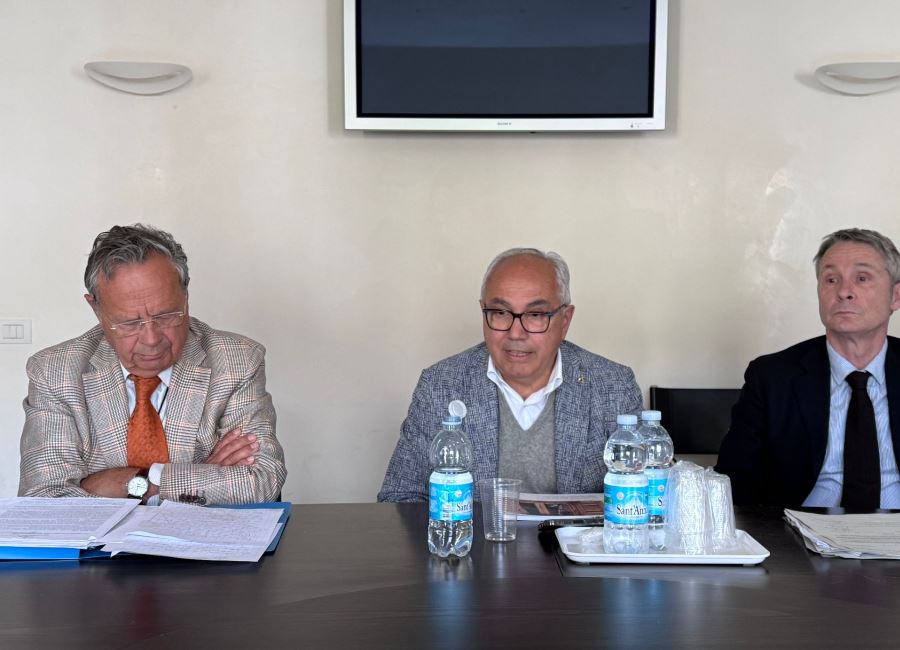 Tre persone al tavolo relatori Boito da sinistra con el braccia conserte Pozza mentre parla e Rossato che guarda avanti. Dietro il muro con lo schermo in alto e due plafoniere