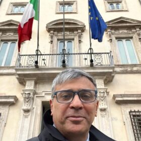 Foto mezzo busto di Anilkumar Dave - Space Economy advisor con sfondo di un palazzo istituzionale con affisse le bandiere italiana e europea Foto mezzo busto di Anilkumar Dave - Space Economy advisor con sfondo di un palazzo istituzionale con affisse le bandiere italiana e europea