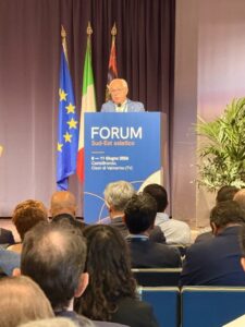 foto presidente Pozza su ambone con scritta forum sud est asiatico e bandiere dietro e persone sedute davanti