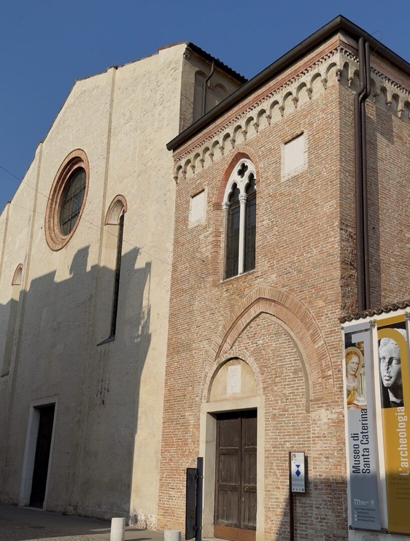 Foto-della-Faccaita-del-Museo-di-Santa-Caterian-in-un-agiornata-di-sole-limpidala-faccaita-e-di-mattoni-antichi-con-una-facciata-piu-alta-con-finestra-a-rosone-e-una-piu-bassa-con-bifore.