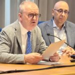 Foto-Presidente-DeBettin-con foglio in mano mentre interviene al tavolo relatori con Federico Callegari a fianco. La foto è un momento della conferenza stampa a Belluno su preparati al futuro