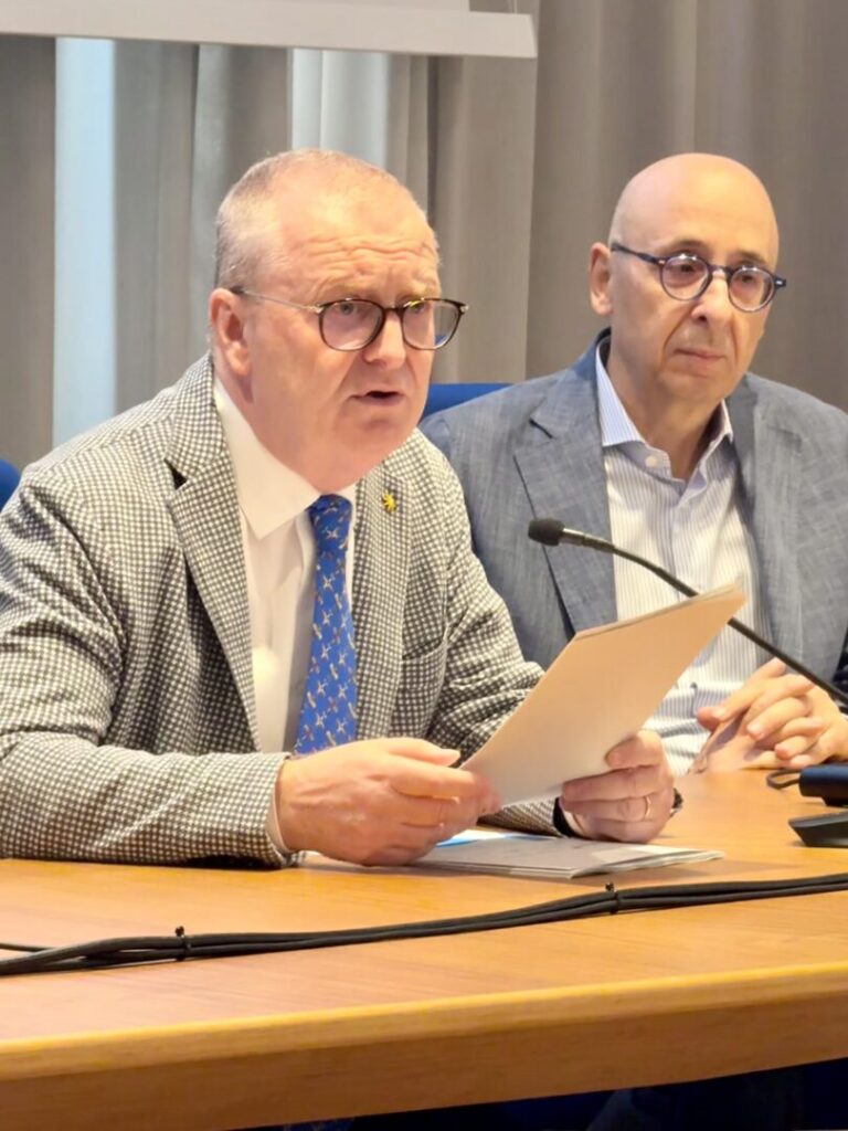 Foto-Presidente-DeBettin-con foglio in mano mentre interviene al tavolo relatori con Federico Callegari a fianco. La foto è un momento della conferenza stampa a Belluno su preparati al futuro